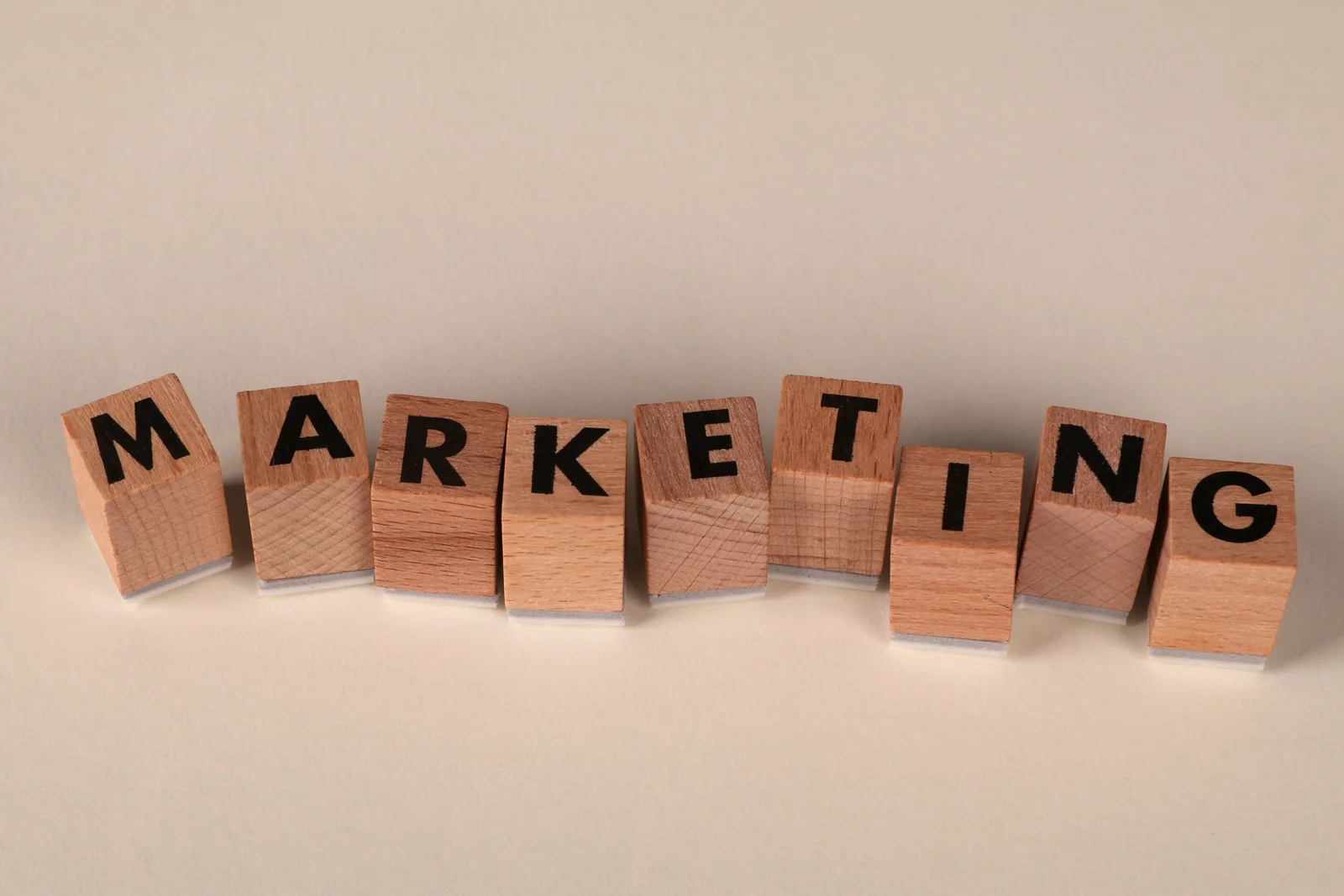 Blocos de madeira com a palavra marketing, representando as técnicas de comunicação usadas para captar atenção.